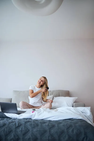 Bella femmina attraente in casa vestiti spazzolatura capelli a letto — Foto Stock