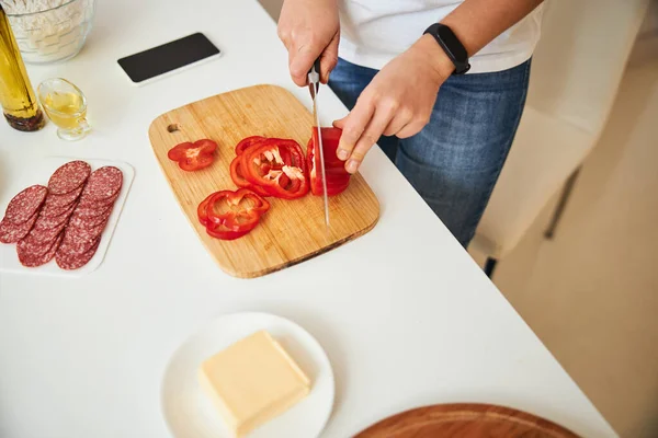 Людина робить гладкі скибочки перцю для їжі — стокове фото
