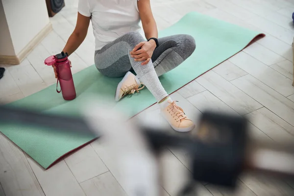Atleta no tapete de exercício segurando um recipiente de plástico — Fotografia de Stock