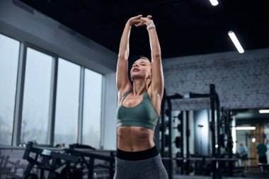 Spor salonunda kolunu kaldıran bir kadın.