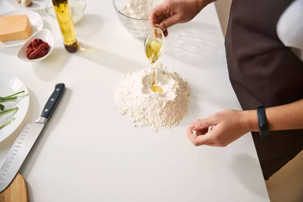 Шеф-повар добавляет оливковое масло при приготовлении теста — стоковое фото