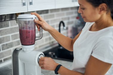 Yoğunlaştırılmış ev hanımı smoothie yapmak için blenderi kullanıyor.