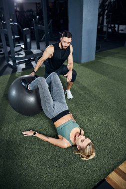 Koç, kadın bacak kıvrımları sırasında bir denge topu tutuyor.