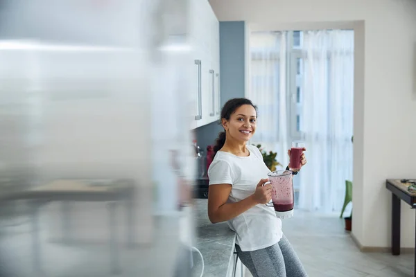 Tevreden fit vrouw met een fruit drankje kijken vooruit — Stockfoto
