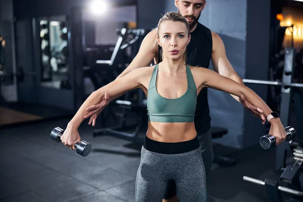 Instrutor espalhando os braços de uma esportista — Fotografia de Stock