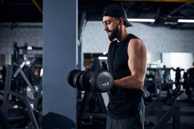 Kaslı adam iki ağır dambıl kaldırıyor.