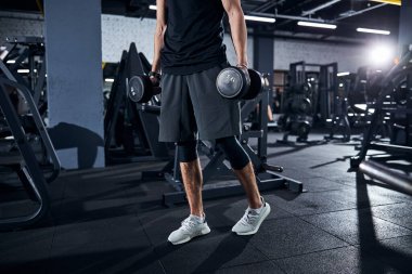 Erkek sporcu dambılları bir yere götürüyor.