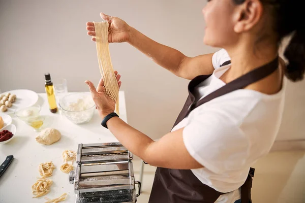 Woman admiring her homemade noodles in the kitchen — Stock Photo, Image