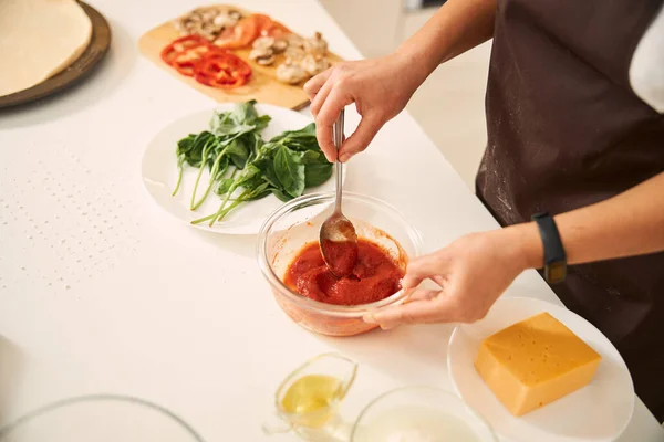 Cozinheiro fêmea misturando pasta de tomate para a refeição — Fotografia de Stock