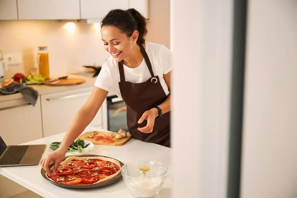 Innholdte damer som tar de siste trinnene i matlagingen av pizza – stockfoto