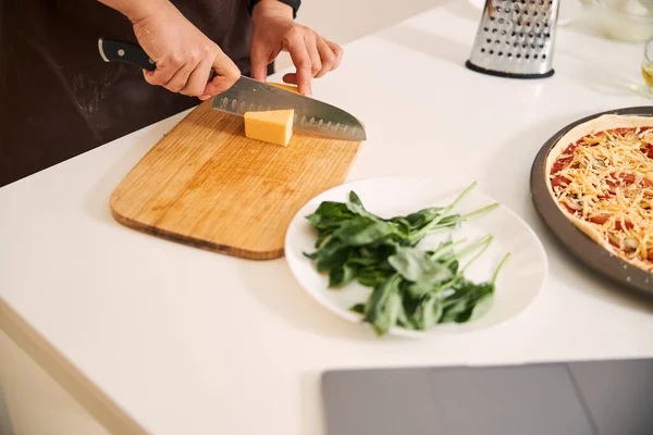 Corte de queijo enquanto faz pizza em casa — Fotografia de Stock