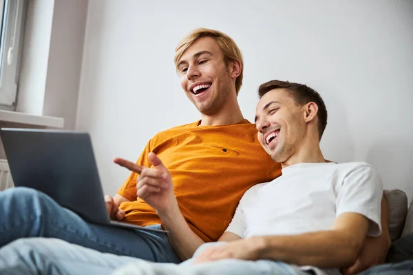 Feliz gay pareja viendo película en laptop en casa —  Fotos de Stock