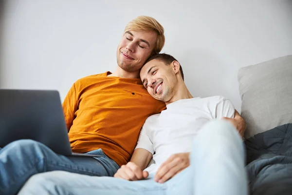 Glad homosexuell par kramas och använda laptop hemma — Stockfoto