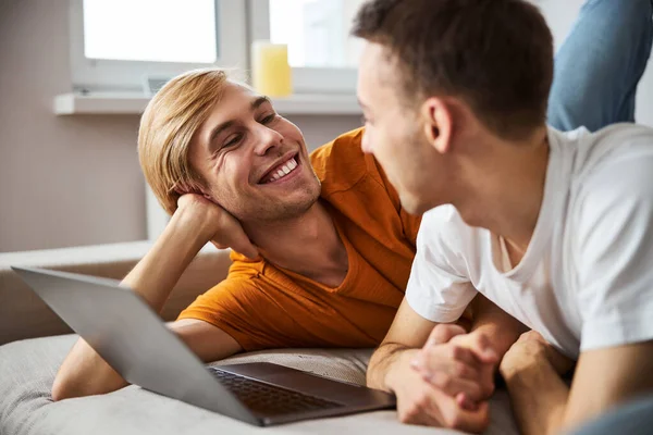 Feliz gay casal passando tempo juntos e usando notebook no casa — Fotografia de Stock