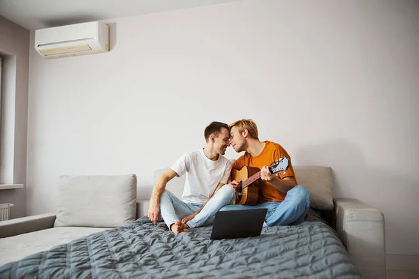 Amar casal gay sentado na cama e tocando as testas — Fotografia de Stock