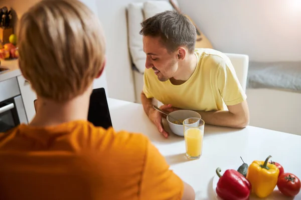 快乐的同性恋夫妇使用笔记本，在家里吃早餐 — 图库照片