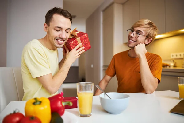 快乐的男人和男朋友坐在桌旁，手里拿着礼品盒 — 图库照片