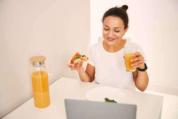 Задоволена молода жінка їсть під час відеодзвінка — стокове фото