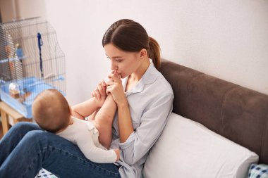 Çekici bir kadın bebeğinin bacaklarını öpüyor.