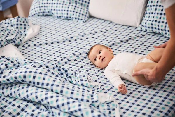 Küçük bebek yatakta yatar ve yan bakar. — Stok fotoğraf