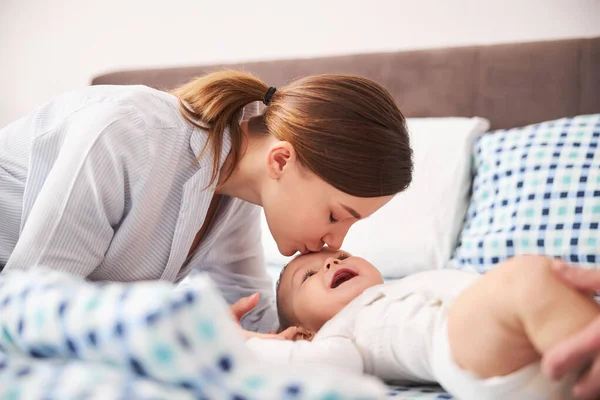 Jonge tedere vrouw zoenen haar kleine kind — Stockfoto