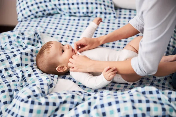 Försiktig mamma bär kroppsdräkt på sitt barn — Stockfoto