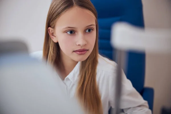 Seriously blonde girl spending time in office of pediactric ophthalmologist — Stock Photo, Image