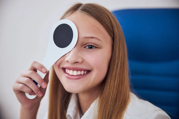 Teenager-Mädchen sitzt im blauen Stuhl und blickt in Medizinschrank voraus — Stockfoto