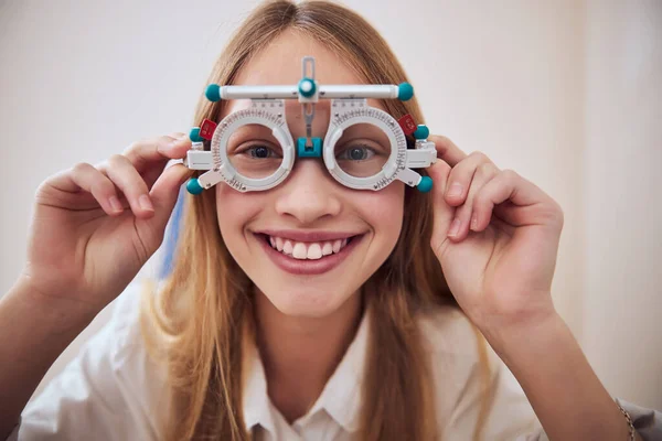 Schöne niedliche Dame hält spezielles Werkzeug in der Hand isoliert auf weißem Hintergrund in Optometristen Kabinett — Stockfoto