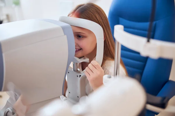 Feliz sonrisa linda chica mirando lámpara de hendidura durante el chequeo médico en el clima ojos en el gabinete optometrista — Foto de Stock