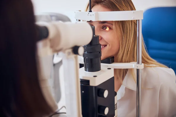 Ενήλικες Καυκάσια γυναίκα με λευκό πουκάμισο ελέγχει την όραση στην οφθαλμολογική κλινική — Φωτογραφία Αρχείου