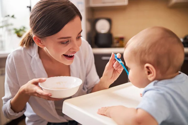 Positivo felice giovane genitore che alimenta il suo bambino — Foto Stock