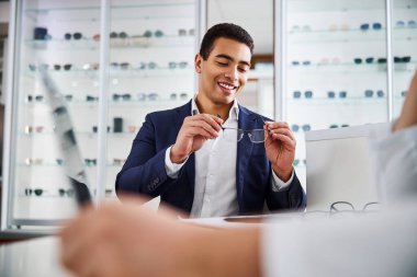 Müşteri elindeki yarı çerçevesiz gözlüklere bakıyor.