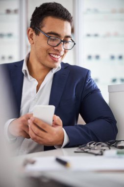 Gözlükçünün masasındaki gözlüğe bakan adam.