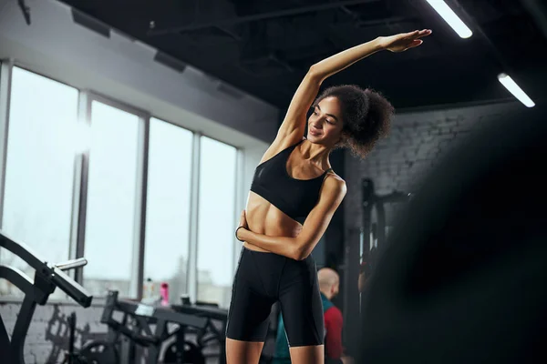 Entzückte Sportlerin macht Dehnübungen mit Freude — Stockfoto