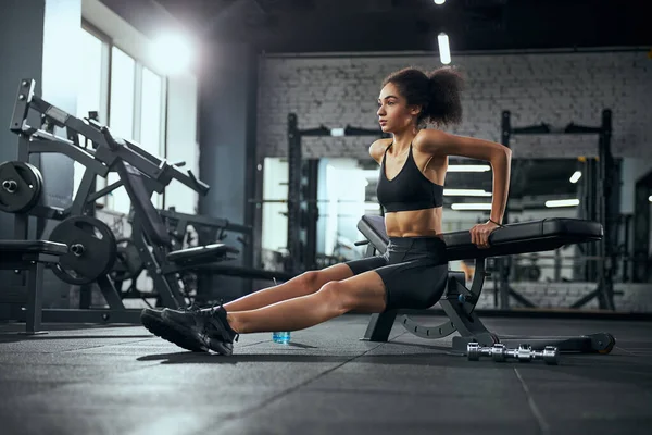 Geconcentreerde internationale vrouw doet workouts voor armen — Stockfoto