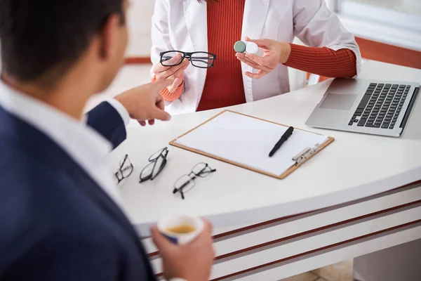 Client pointant vers les lunettes élégantes dans les mains de l'opticien — Photo