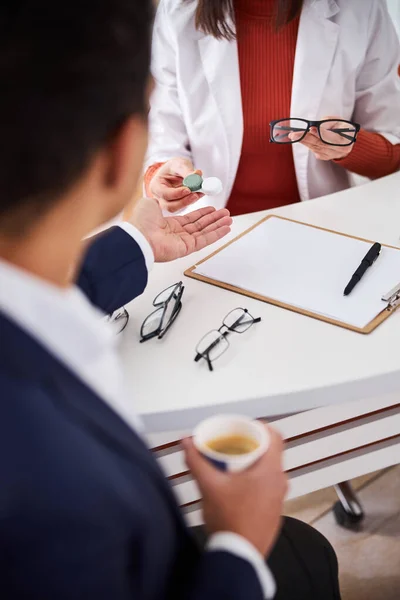 Optométriste expérimenté montrant des lentilles de contact et des lunettes à un acheteur — Photo
