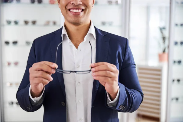 Comprador alegre sosteniendo un par de gafas en sus manos — Foto de Stock