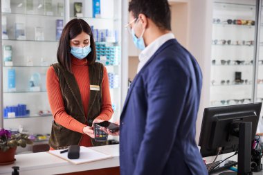 Alıcı kasada akıllı telefonuyla ödeme yapıyor.