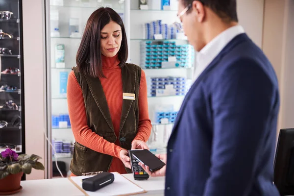 Buyer paying with a mobile device in an optical store — Stock Photo, Image