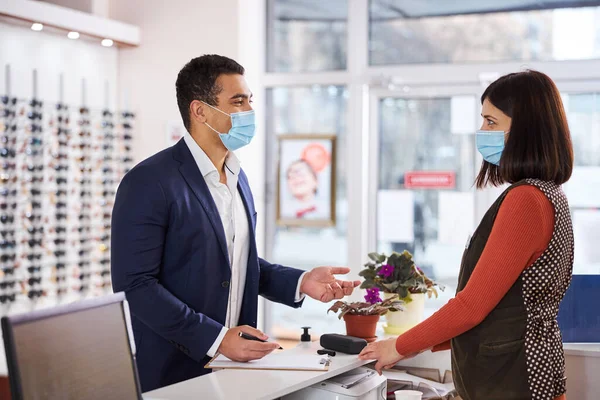 Klant met gezichtsmasker in gesprek met een optometrist — Stockfoto