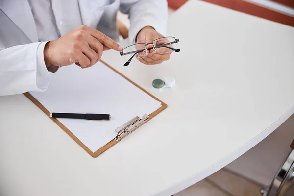 Optician pointing his index finger at a spectacle frame — Stock Photo, Image