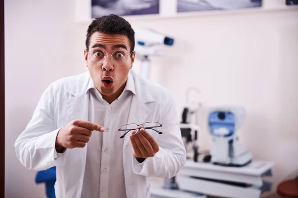 Opticien surpris dans un blouse de laboratoire tenant des lunettes semi-sans jante — Photo