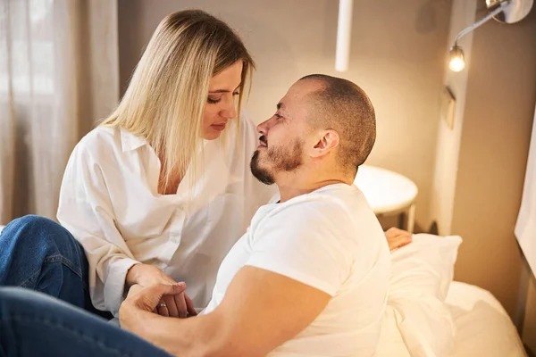 Mulher loira e seu marido sentados na cama — Fotografia de Stock