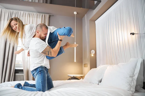 Fröhlicher Mann unterhält seine Frau im Schlafzimmer — Stockfoto
