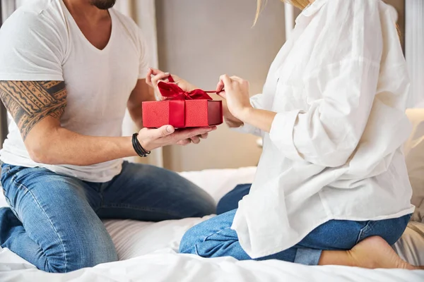Blond vrouwtje uitpakken van een cadeau gegeven door haar echtgenoot — Stockfoto