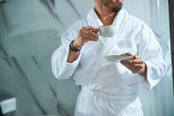 Männchen mit Schokoladenmacarons und einer Teetasse in der Hand — Stockfoto