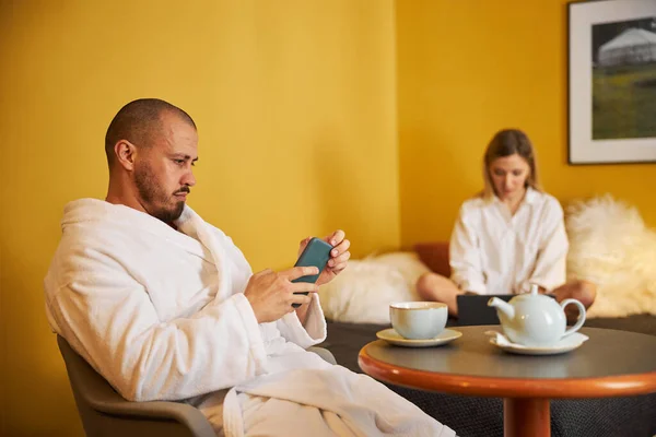 Focado homem e sua esposa usando seus gadgets — Fotografia de Stock