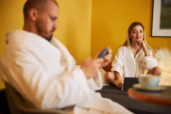 Улыбающаяся женщина восхищается своим мужем смартфоном — стоковое фото